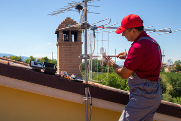 Image of a handyman who mounts the antenna for the TV on the roof of the house. Do-it-yourself antenna job