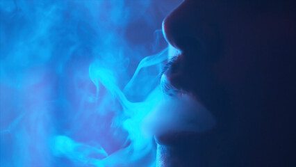 The mouth of a young man smoking the traditional hookah in the dark room, bad habits concept....