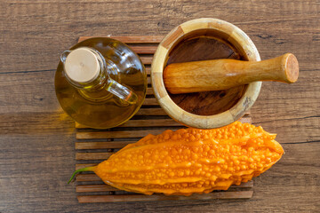 A Momordica charantia, mortar and pestle, and olive oil on the table. Top view.Kudret Narı.Karela.Bitter Melon.