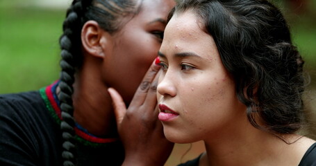 Obraz premium Woman telling secret to friend ear. Friends together sharing gossip