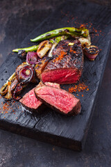 Barbecue dry aged wagyu roast beef steak with BBQ chili and onion rings served as close-up on a...