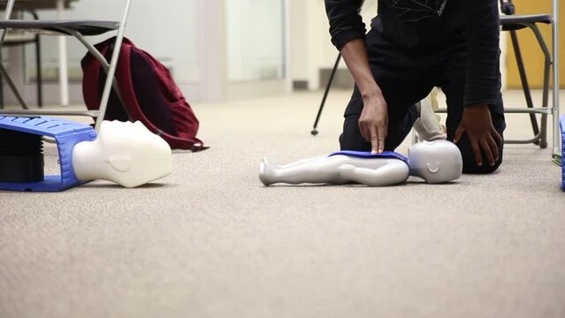 Staff practicing first aid cpr with AED machine and dummy dolls