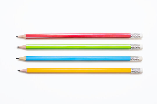 Four multi-colored pencils on a white background. Red, green, blue and yellow pencils lie parallel to each other on a white isolated background