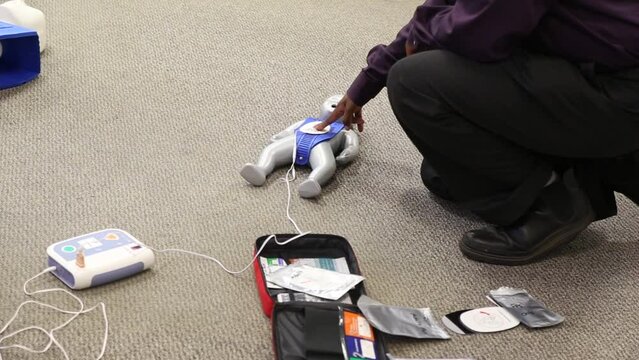Staff practicing first aid cpr with AED machine and dummy dolls