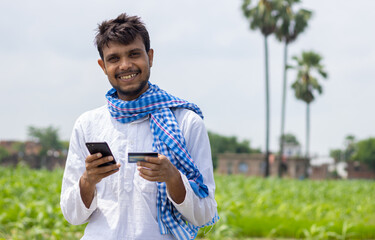 portrait of indian farmer with smartphone and debit cards