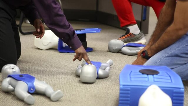 Staff practicing first aid cpr with AED machine and dummy dolls