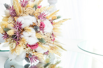 Dried cotton flowers and wheat ear in a bohemian bridal bouquet.