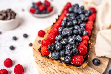 Fruit Tart full of Berries with chocolate and cream on cookie crust. European dissert. 