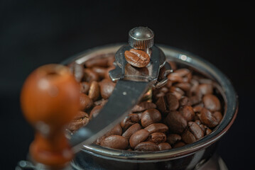 Grains of delicious roasted coffee in a manual mechanical coffee grinder.
