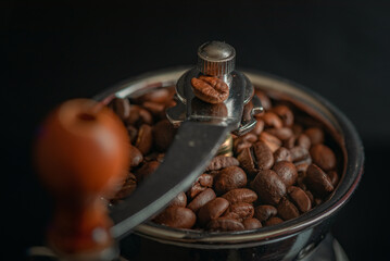 Grains of delicious roasted coffee in a manual mechanical coffee grinder.