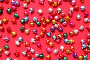 Little christmas colourful jingle bells on red background with copy space for text. Holiday festive happy new year concept. Idea for greeting postcard, poster, banner. Mock up, flatlay, top view
