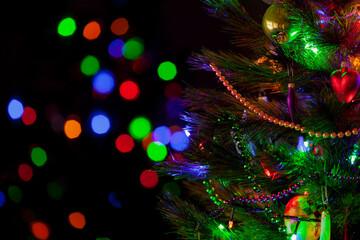 Fototapeta na wymiar Christmas tree with toys and garlands stands in dark room....
