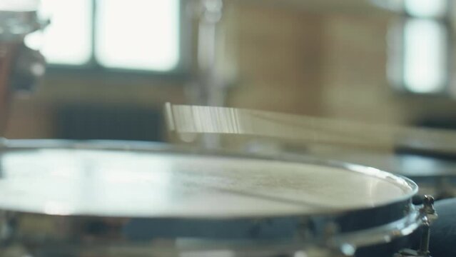 Close up shot of drumsticks hitting head of snare drum as musician playing in studio