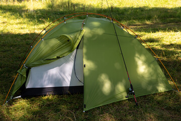 modern green camping tent with outdoor frame set up in the forest