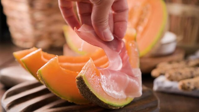 Italian prosciutto crudo with melons. Slices of traditional ham wrapped around melons. Tasty appetizer. Food background. Close up. Snack for wine for an aperitif