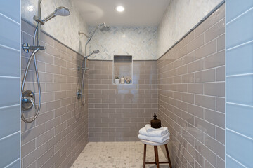 Walk in shower with double shower heads and multiple tile patterns.