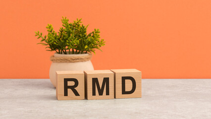 word RMD on wooden cubes. green flower on beautiful orange background. business concept. copy space.