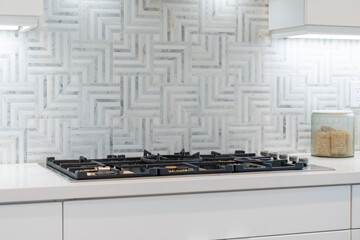 Modern kitchen details of flat top stove with pattern tile backsplash.