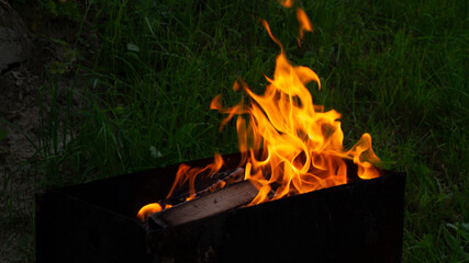 Obraz premium a fire is burning in the barbecue. firewood on the grill in flames