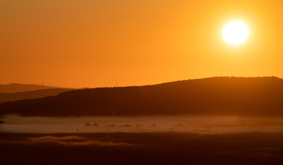 Fototapeta na wymiar Orange sky, mist and sun on top of the mountain