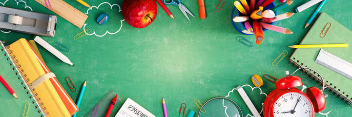 Back to school concept with school equipment and red alarm clock on green chalkboard background 3D...