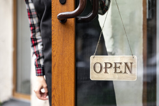 woman holds a wooden sign with the inscription open or closed at the door of a restaurant or coffee shop. the working hours of the restaurant or the food and beverage delivery service. to the courier