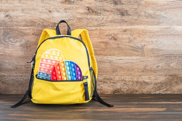 Sensory fidget toys in school bag over wooden background with copy space.