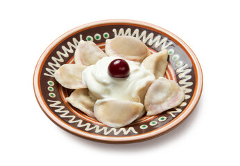 Traditional Ukrainian dumplings, vareniki with cherries and sour cream in a ceramic painted bowl isolated on white background. - 520665637