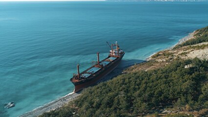 Aerial view of large cargo ship in still blue water near coastline. Shot. Sea transportations