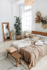 Cozy rustic bedroom with boho ethnic decor. Bright spacious apartment with large windows. Wooden...