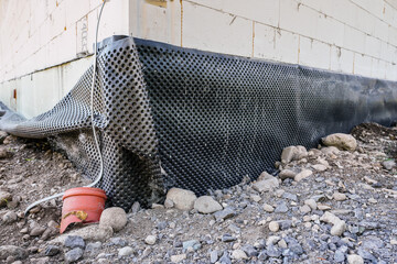 Black dimpled house foundation drain waterproofing membrane installed on newly build wall ground