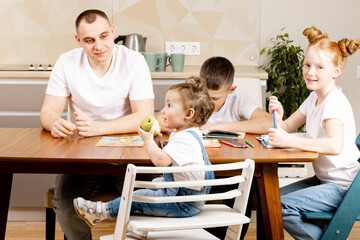 the child eats an apple at the kitchen table, the whole family is around