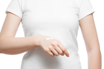 Cropped shot of a woman in white t-shirt applying hand cream, isolated on white. Well-groomed short natural nails.