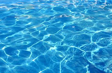 Fototapeta na wymiar Water background of the pool with the effect of small ripples and sunlight.