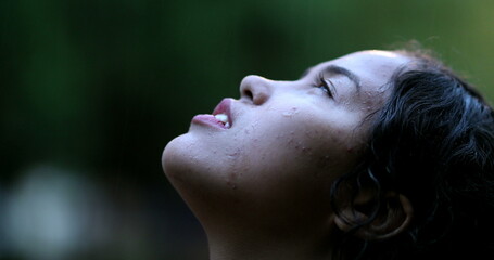 Young woman standing in the rain outside, girl opening eyes to sky feeling HOPE in raining day