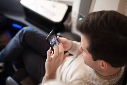 Man browsing on mobile phone in business class on airplane