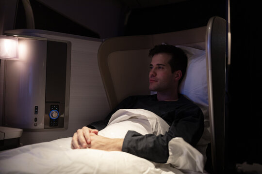 Airline passenger reclining in the seat turned to a bed in the first class cabin.