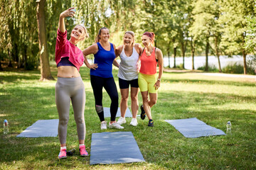 Group of women taking selfie in park during outdoor yoga class