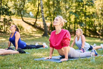 Group of women stretching in park during outdoor fitness class