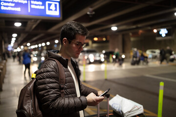 Man at airport terminal ordering taxi using smart phone app