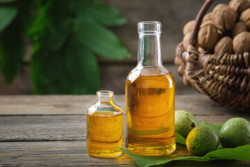 Bottles of essential nut oil, green and ripe walnuts. Basket of nuts on background.
