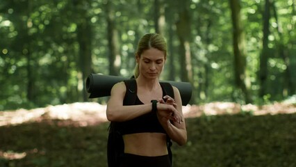 Sporty woman tourist with backpack looking at her smartwatch, using gps app to create right route, empty space - Powered by Adobe