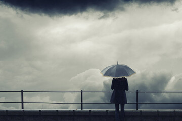 Woman with umbrella standing on the rain during autumn storm