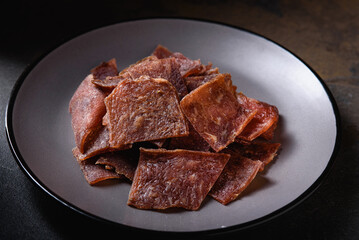 View from Above. Flat Layout. Snack for Beer. Dried Pork Chips with Seasonings on Gray Plate.