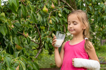  Cute little girl with a broken arm in a cast drink milk and enjoy. Rehabilitation after a fracture