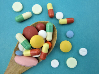  Various pharmaceutical medicine pills, tablets and capsules on wooden spoon     