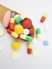   Various pharmaceutical medicine pills, tablets and capsules on wooden spoon 