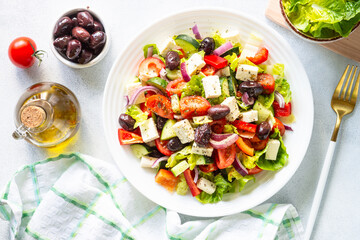 Greek salad with olives, feta cheese and fresh vegetables on white.