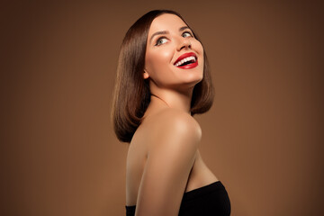 Young stunning lady with short bob hairdo look aside posing profile view on brown background beauty...