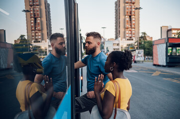Multiracial friends entering the pubic transport while at a bus stop